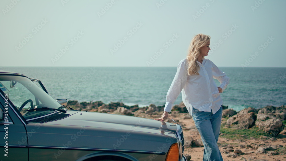 Fototapeta premium Stylish model posing retro car at summer seacoast. Woman standing sunny beach.
