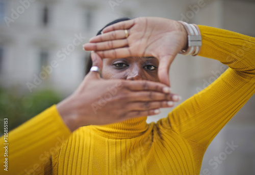 Black adult woman forms a frame around her eyes with her hands