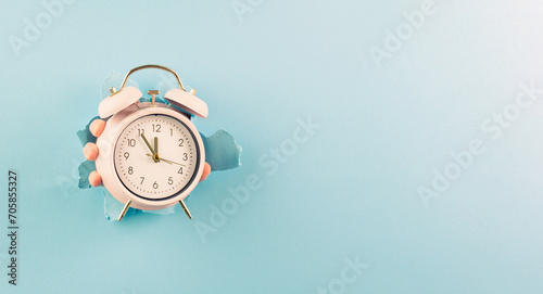 Hand holding alarm clock, torn paper hole, time management, reminder and planning, finish a deadline, timetable and stress, countdown
 photo