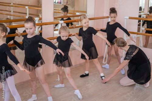 Fototapeta Naklejka Na Ścianę i Meble -  Children's ballet school. Caucasian woman teaching ballet to little girls. 