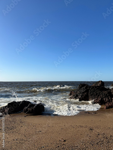 Waves crash against the rugged rocks at Punta del Este's beach in Uruguay, creating a spectacle of powerful collisions and foamy sprays against the coastal landscape.