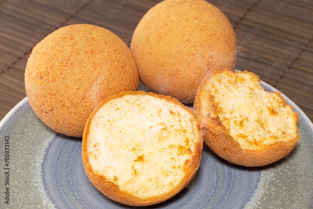 Delicious hot Colombian fritters on a plate on a wooden background. A steamy bread. Colombian Christmas food concept. Delicious hot Colombian fritters on a plate on a wooden background. A steamy bread. Colombian Christmas food concept.