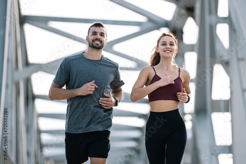 Happy athletic couple having fun while running outside. Adult sport man and woman friends training together.