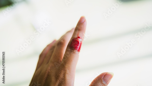 The hand of a person with a wound on the index finger and the bleeding does not stop even though it is covered with a plaster, concept of health insurance and accidents