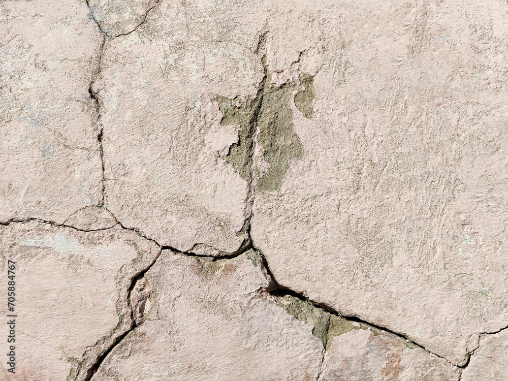 Obraz premium The wall of an old building with crumbling plaster and many winding, deep cracks. Copy space. Selective focus.