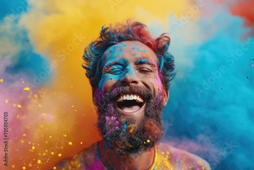 Bearded man having fun during Holi festival, portrait of laughing person with paint on face. Guy is in cloud of colorful powder. Concept of India, party, color, travel people