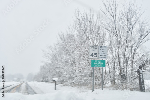 City Limit Sign and Speed Limit Sign by a Snowy Road