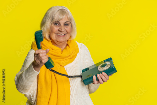 Hey you, call me back. Senior old woman talking on wired landline vintage telephone of 80s, advertising proposition of conversation, online shopping, hotline. Mature grandmother on yellow background