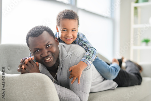 American father with little boy at home lay on sofa