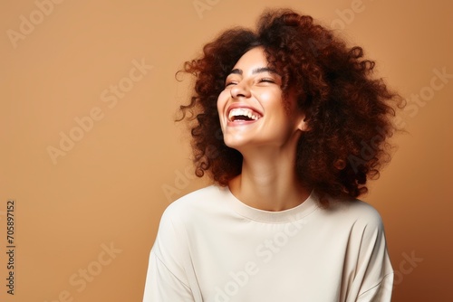 A laughing woman on a studio pastel background.