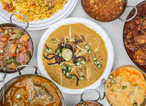 Chicken haleem, chicken karahi, biryani, beef nihari, curry pakora, chanay, aloo shimla mirch and keema isolated on grey background top view of pakistani and assorted indian spices food variety
