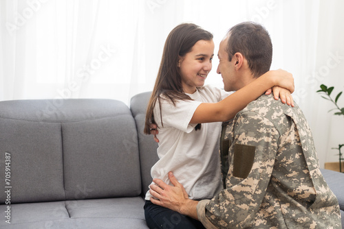 Young man in military uniform with his wife on sofa at home photo