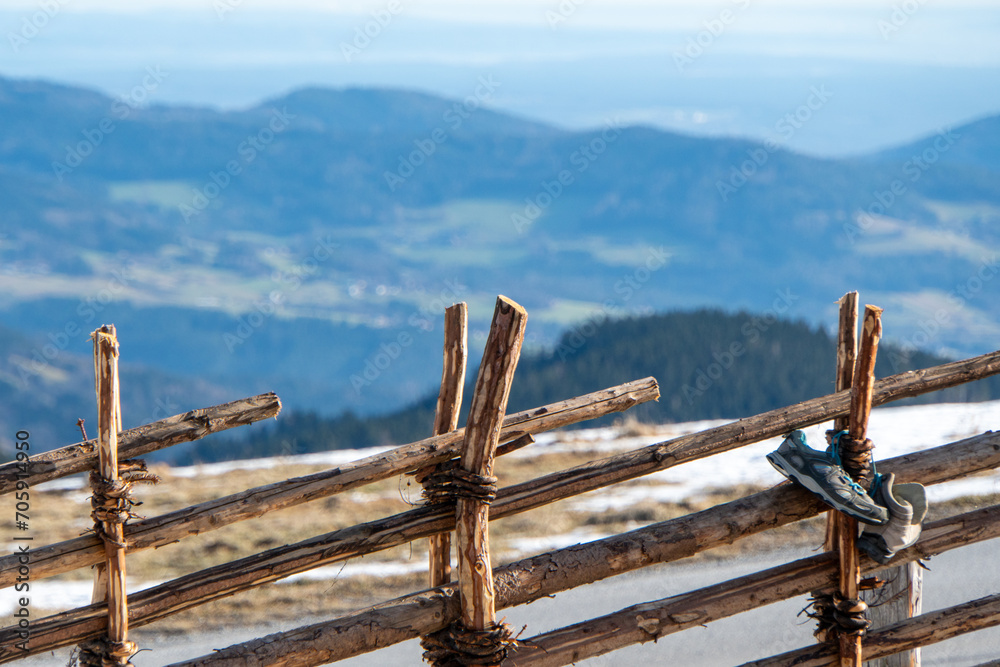 Holzzaun mit Schuhen und verschneiter Landschaft im Hintergrund