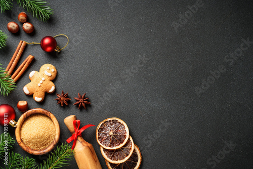Christmas food and ingredients for cooking at black. Gingerbread cookies, spices and Christmas decorations. Flat lay with space for text.