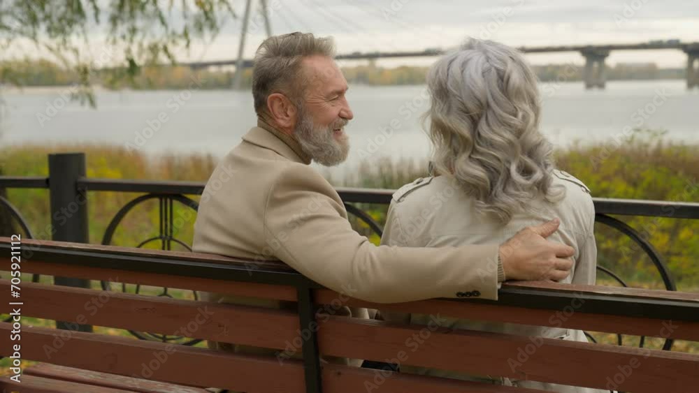 Back view happy senior mature 60s husband wife hugging on bench outdoors healthy retirement couple mid aged woman man talk laugh relax enjoy romantic weekend together love old age in city park nature Back view happy senior mature 60s husband wife hugging on bench outdoors healthy retirement couple mid aged woman man talk laugh relax enjoy romantic weekend together love old age in city park nature