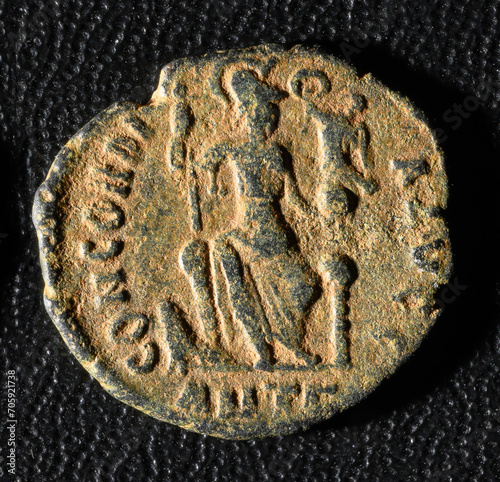 Goddess Concordia on Ancient Roman coin, old worn metal money isolated on black background. Theme of vintage copper texture, Rome and history. photo