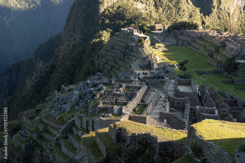 Part of the Machu Picchu citadel on the edge of a cliff and beginning to receive the morning sun