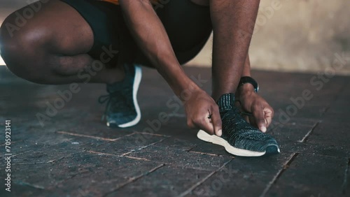 Man, hands and tie shoes for running, fitness or workout exercise on outdoor concrete floor. Closeup of African male person, runner or athlete tying shoe lace in preparation for cardio training photo