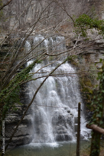 A stunning waterfall cascades over rocky cliffs, surrounded by lush greenery, creating a serene, picturesque natural scene photo