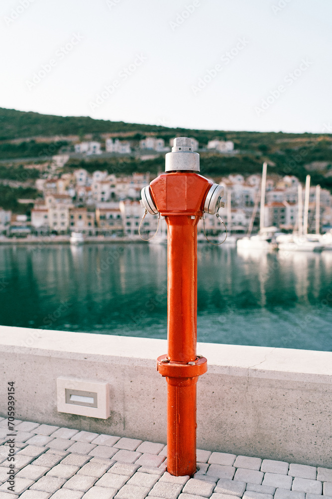 Red fire hydrant stands on a pier by the sea