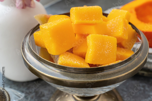 Homemade pumpkin and agar-agar gummies. Orange jelly candies served on a plate with pumpkin in the background.