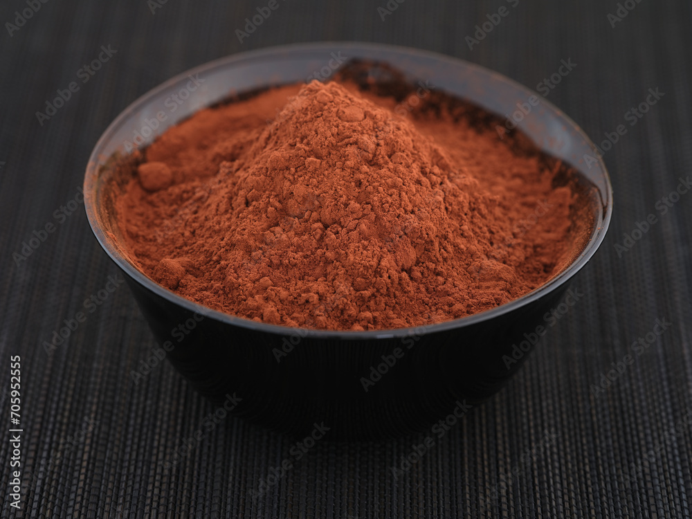 Organic cocoa powder in a black bowl. Close up. Organic cocoa powder in a black bowl. Close up.