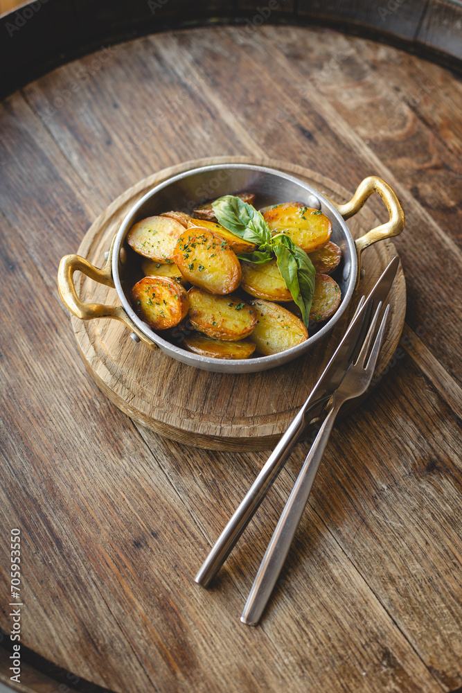 Country potatoes, fried potato slices in a frying pan on a wooden background.