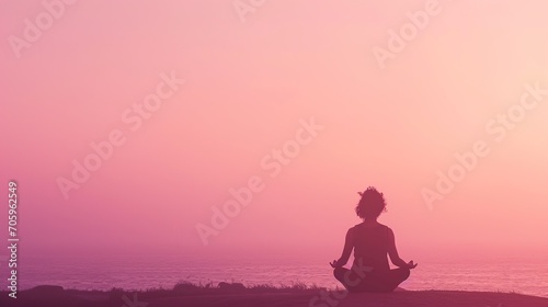 A peaceful silhouette of a person in meditation pose at sunset, with a tranquil sea and pink-hued sky in the background. 