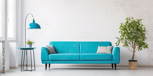 Modern apartment with turquoise couch and workspace against white wall.