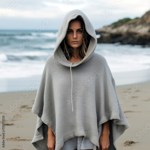 A woman wearing poncho with hoodie on the beach. photo