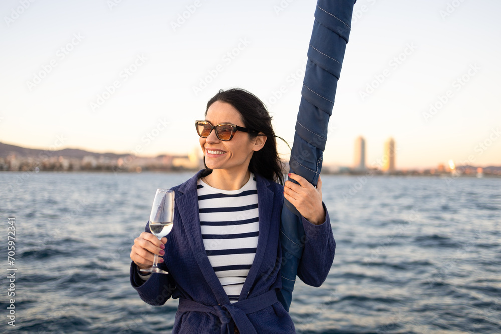 Young woman with glass of drink standing against sea Young woman with glass of drink standing against sea