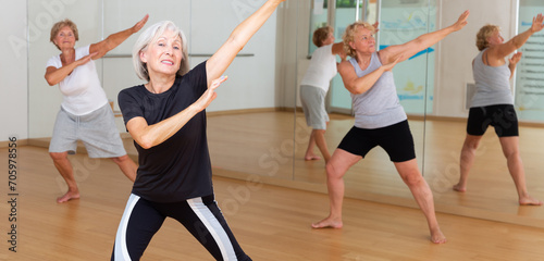 Active mature woman visiting choreography class with group of aged females, learning modern dynamic dances.