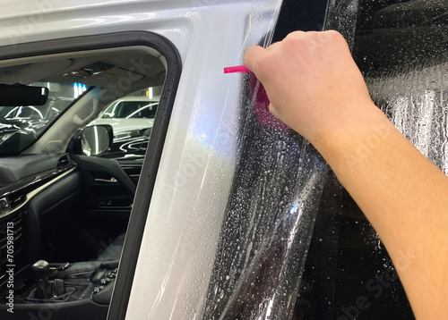 Car wrapping. A car wrapping specialist applies a polyurethane film to the car. Selective focus. PPF protective film against chips and scratches. Paint protection. 