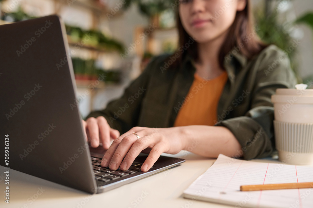 Woman working on her laptop sitting at her workplace, focus on hands Woman working on her laptop sitting at her workplace, focus on hands