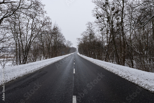 Panorama ulicy zimą, droga biegnąca wzdłuż kadru w śnieżny dzień o wieczornej porze w zachodniej Polsce