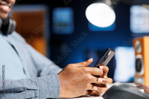 While taking web educational classes, male worker examines social media software on phone and sends texts. Young man texting SMS messages and browsing headlines on internet.