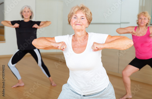 Aged women performing modern dance during their group training in fitness room.