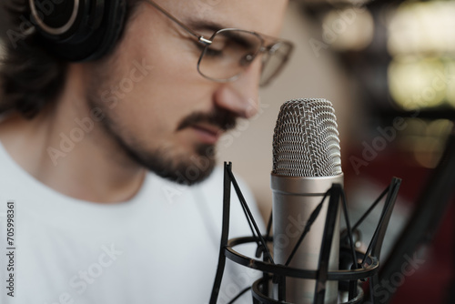 Close-up of a male artist with headphones performing or recording vocals with a studio microphone photo