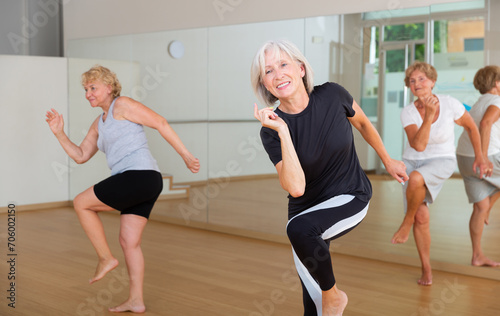 Portrait of smiling mature woman enjoying active dancing during group training in dance studio.