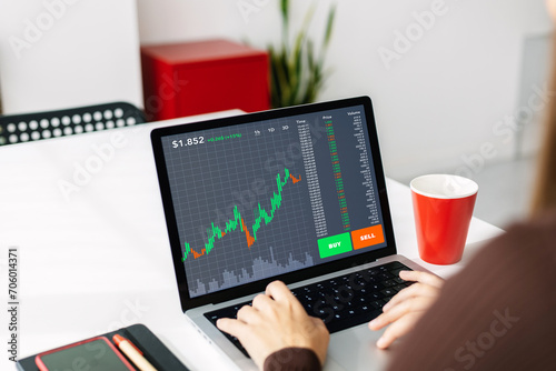 Fotografie Young woman investor working on laptop at home