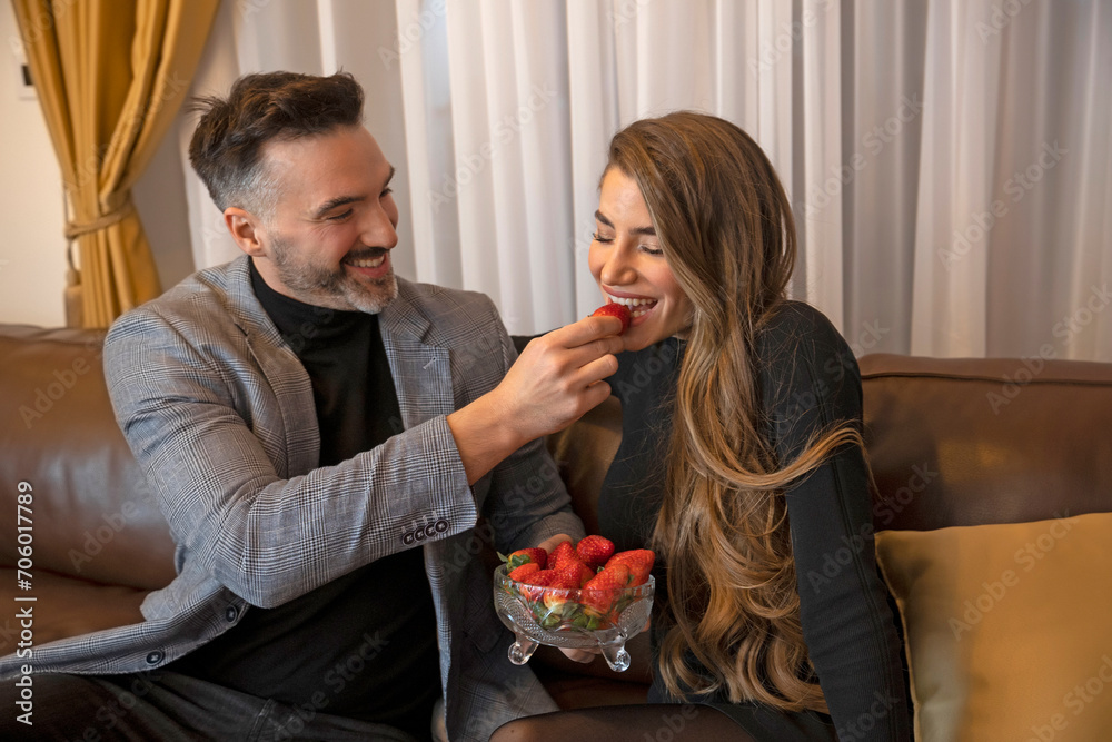 Naklejka premium Handsome man feeding his girlfriend with strawberry