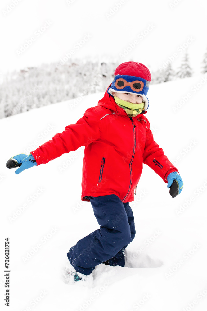 Little boy on a cold winter day in the mountains. Playing with snow.