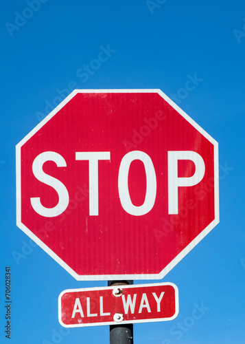 Stop sign under blue sky in USA with all way addition