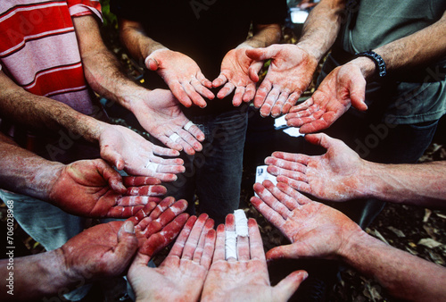 The chalk-covered and weathered hands of a group of rock climbers palm up and facing eachother in a circle photo