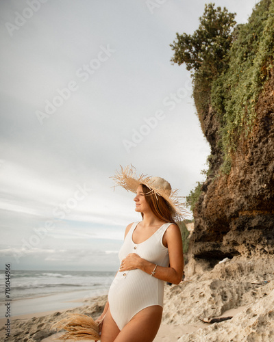 Young pregnant woman walking on the beach, waiting for baby birth lloking at happy bright future photo