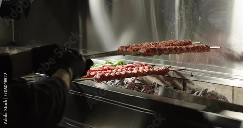 Chef puts raw kebabs on barbecue charcoal grill. Meat and vegetables on grill. Traditional Turkish kebab grilled on skewers photo
