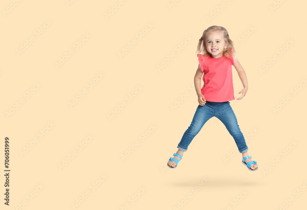 Cute girl jumping on beige background, space for text Cute girl jumping on beige background, space for text
