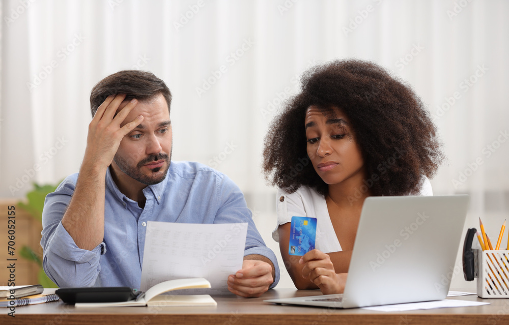 Confused couple with debt notification and credit card planning budget at table indoors. Financial problem Confused couple with debt notification and credit card planning budget at table indoors. Financial problem