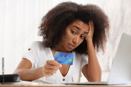 Confused woman with credit card planning budget indoors. Debt problem