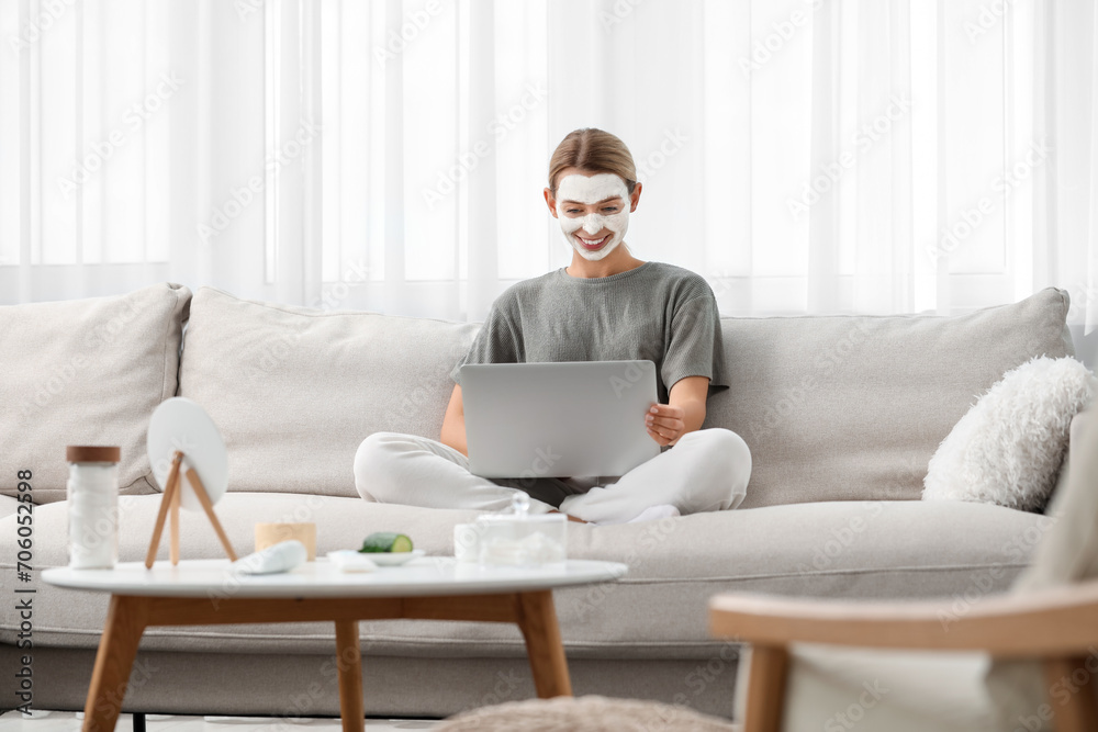 Young woman with face mask using laptop on sofa at home. Spa treatments Young woman with face mask using laptop on sofa at home. Spa treatments